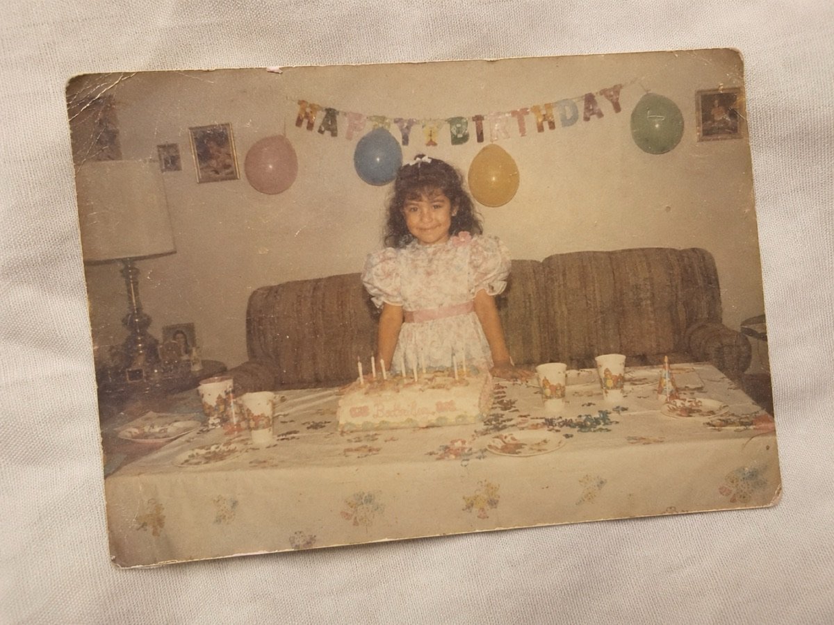 Foto original: niña en su fiesta de cumpleaños, frente al pastel