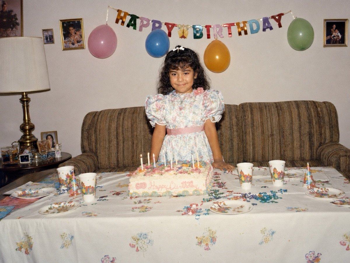 Foto restaurada: niña en su fiesta de cumpleaños, frente al pastel